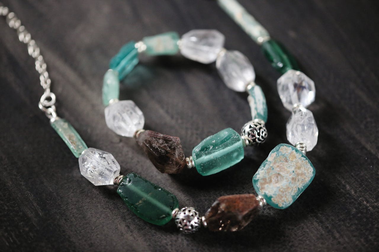 Close-up of a beautiful gemstone necklace and bracelet set on a dark wooden background.
